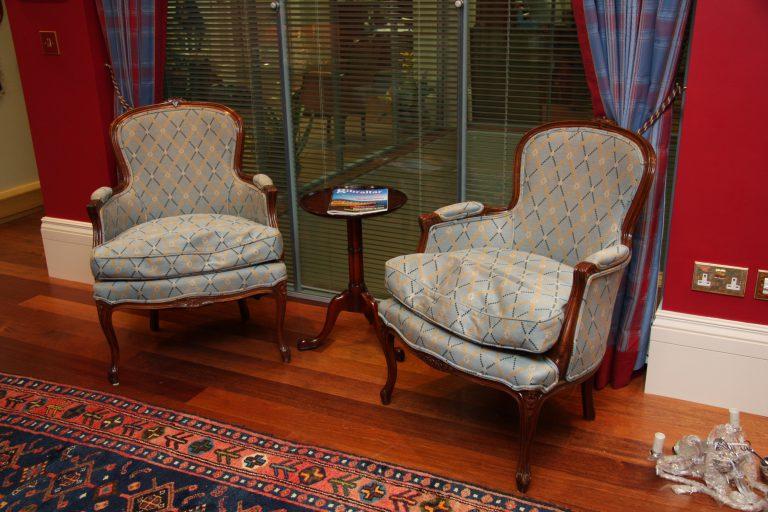 Matching antique armchairs in red walled office