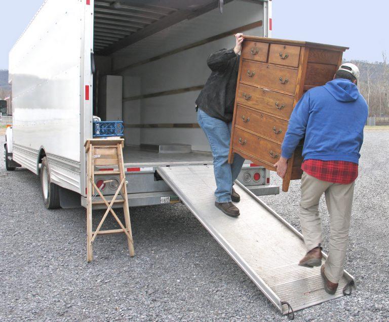 two,men,carry,chest,of,drawers,onto,a,moving,van