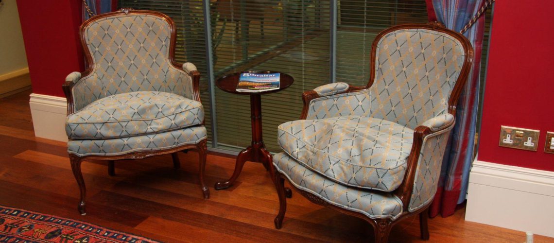 Matching antique armchairs in red walled office