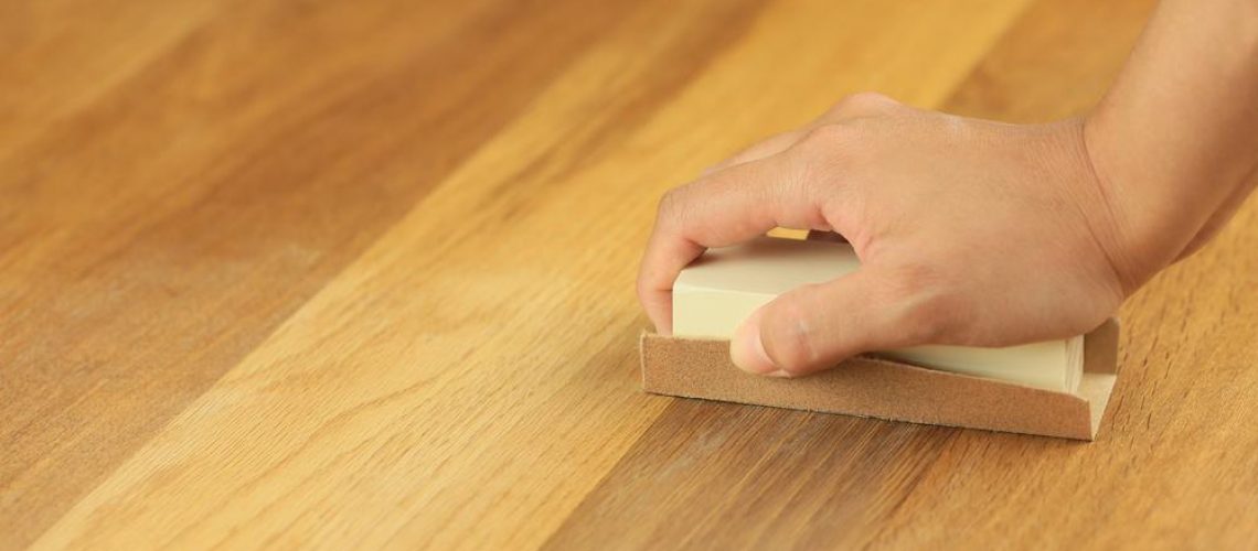 man restoring wooden flooring with sandpaper