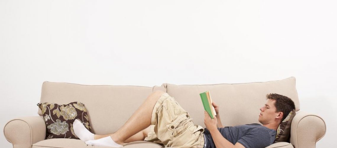 a,young,man,lays,down,and,reads,on,a,couch